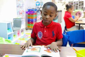 A boy reading a book from Book'em at our Read Me Day celebration.